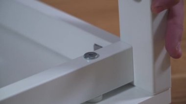 Yeni eve taşınıyorum. Kutuları açmak ve mobilyaları monte etmek. Adam talimatları okuyor ve mobilyaları monte ediyor. DIY. Erkek, yeni beyaz mobilyalar kuruyor. Kendiniz yapın. Mobilya montaj süreci