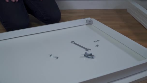 Procesul de asamblare a mesei albe DIY la domiciliu. Instalare mobilă. Casa nouă și omul de asamblare mobilier face-o singur. Masa de asamblare masculină din cutie conform instrucțiunilor de pe podea — Videoclip de stoc