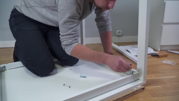 DIY biały proces montażu stołu w domu. Instalacja mebli. Nowy dom i człowiek montujący meble robią to sami. Męski stół montażowy z pudełka zgodnie z instrukcją na podłodze — Wideo stockowe