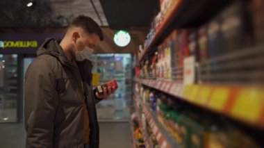 Markette alışveriş yapan, alışveriş sepetiyle yürüyen, süpermarkette karantina sırasında gerekli malzemeleri alan, koruyucu maske takan bir adam. Yeni normal, covid 19 ve alışverişler. Maske yoksa giriş de yok