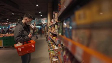 Markette alışveriş yapan, alışveriş sepetiyle yürüyen, süpermarkette karantina sırasında gerekli malzemeleri alan, koruyucu maske takan bir adam. Yeni normal, covid 19 ve alışverişler. Maske yoksa giriş de yok