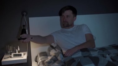 Depresyon ve uykusuzluktan muzdarip beyaz bir adam TV izlerken kendini eğlendirmeye çalışıyor, geceleri uzaktan kumandayla kanal değiştiriyor.