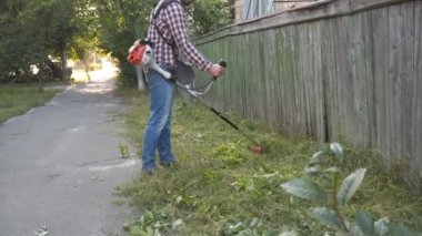 Çim biçme makinesi işçisi çim biçiyor. Kulak koruyucusu takan bir adam çim biçme makinesiyle çim biçiyor. Bahçıvan köyde çim biçer yol boyunca gaz tırpanı kullanır. Çim biçme işlemi