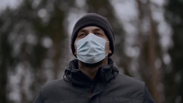 Kaukasischer Mann nimmt Maske ab und atmet frische Luft ein, Wald vor verschwommenem Hintergrund, Impfstoff gegen COVID-19-Pandemie, soziale Distanzierung, neuer normaler Lebensstil. Coronavirus ist vorbei — Stockvideo