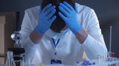 Genç doktor çok yorgun ve kovid 19 ile enfekte olmuş, üzgün, elleriyle başını kaldırmış, maske koronavirüs üzerine yazılmış sözlerle kafasını maskesine kaldırmış. Salgın sırasında tıbbi sistem çökmesi