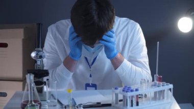 Yorgun, bitkin, yıkılmış doktor bilim adamı, uzun bir vardiyadan sonra, yüz maskesi takmış, yazı koronavirüsüne sahip. Kayıp umut kavramı, Covid-19 hastalığı, küresel salgın, SARS-CoV-2