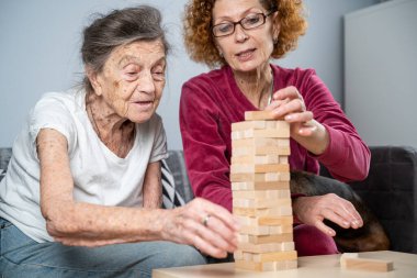 Emekli anne ve kızı evde birlikte vakit geçirir, masa oyunu oynar ve dachshund köpeği okşarlar. Kafkas kıdemli kadın bakım evinde gönüllü asistanı olan ahşap bloklardan bir kule inşa ediyor..
