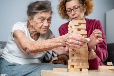 Emekli anne ve kızı evde birlikte vakit geçirir, masa oyunu oynar ve dachshund köpeği okşarlar. Kafkas kıdemli kadın bakım evinde gönüllü asistanı olan ahşap bloklardan bir kule inşa ediyor..