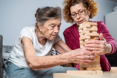 Emekli anne ve kızı evde birlikte vakit geçirir, masa oyunu oynar ve dachshund köpeği okşarlar. Kafkas kıdemli kadın bakım evinde gönüllü asistanı olan ahşap bloklardan bir kule inşa ediyor..