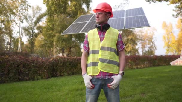 Succesvolle meester van zonnepaneel installatie. Technicus portret tegen zonnecentrale. Concept hernieuwbare energie, technologie, elektriciteit, diensten, groene stroom. Trotse werker in harde hoed — Stockvideo