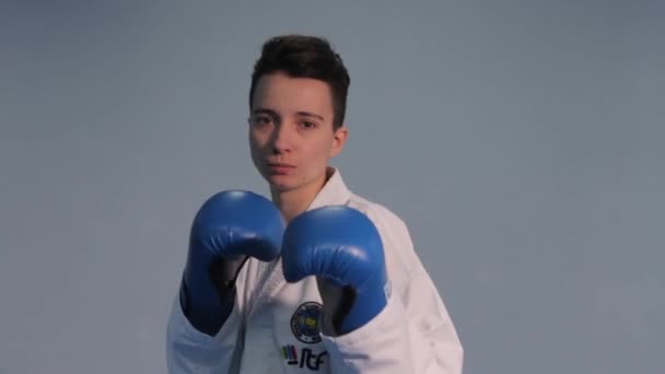 Karate- und Taekwondo-Frau im weißen Kimono mit schwarzem Gürtel trainiert Schläge und Tritte in blauen Sporthandschuhen. Kämpferin beim Kampfsport. Taekwondo-Spieler üben. Ukraine, Kiew 20. März 2017 — Stockvideo