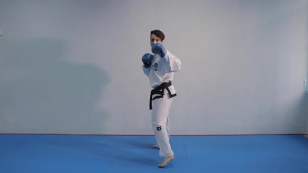 Γυναίκα taekwondo μαχητής εκπαιδεύει σκιά πυγμαχία γροθιές και κλωτσιές. Κορίτσι που φοράει λευκό κιμονό και κάνει πολεμικές τέχνες. Γυναίκα σε κιμονό εξάσκηση taekwondo. Ουκρανία, Κίεβο 20 Μαρτίου 2017 — Αρχείο Βίντεο