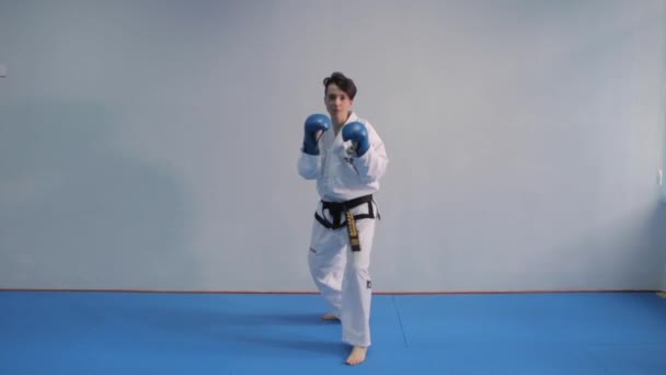 Kobieta trenuje sztuczki taekwondo na siłowni. Białe kimono pokazuje technikę karate. Koncepcja sztuki walki. Sportowiec wykonuje tradycyjne połączenie ciosów. Ukraina, 20 marca 2017 — Wideo stockowe