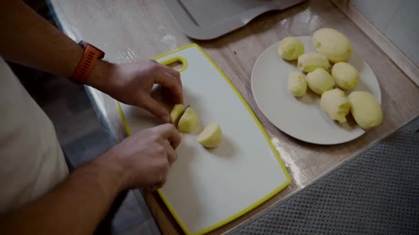 Gezond eten. Handen close-up mannetje snijdt rauwe gewassen aardappelen op een snijplank thuis in de keuken. Verrassing, hulp voor de vrouw. Vegetarische of veganistische levensstijl. Een man die thuis kookt. Groenten versnijden — Stockvideo