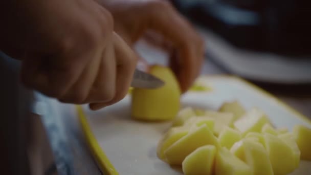 Gesunde Ernährung. Männer in Großaufnahme schneiden roh gewaschene Kartoffeln zu Hause in der Küche auf einem Schneidebrett. Überraschung, Hilfe für Ehefrau. Vegetarische oder vegane Lebensweise. Der Mensch kocht zu Hause. Gemüse schneiden — Stockvideo