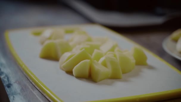 Kaukasier hackt zu Hause in der Küche Kartoffeln aus nächster Nähe. Konzept für gesunde Ernährung. Frisch gewaschene Kartoffeln von Hand auf einem Schneidebrett schneiden. Koch, Vater, Herd. Frische Bio-Kartoffelscheiben — Stockvideo