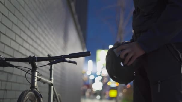 Şehir bisiklet güvenlik teması. Teslimatçı gece caddelerinde bisiklet sürmeden önce kask takıyor. İşten sonra eve bisikletle gidip kaskını takan bir erkek. Döngü koruması — Stok video