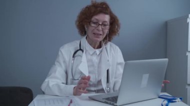 Teletıp hizmetleri. Ana bakım konsültasyonları, psikoterapi, acil servisler. Bilgisayarda online danışmanlık yaparken konuşan ve el kol hareketi yapan bir kadın doktor. Tıp, sağlık hizmeti kavramı