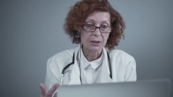 Kobieta pracownik służby zdrowia daje leczenie online. Asystent medyczny nosi kasetę wideo dzwoniącą do odległego pacjenta na laptopie. Koncepcja telemedycyny. Internetowe spotkanie aplikacji lekarza wirtualne spotkanie — Wideo stockowe