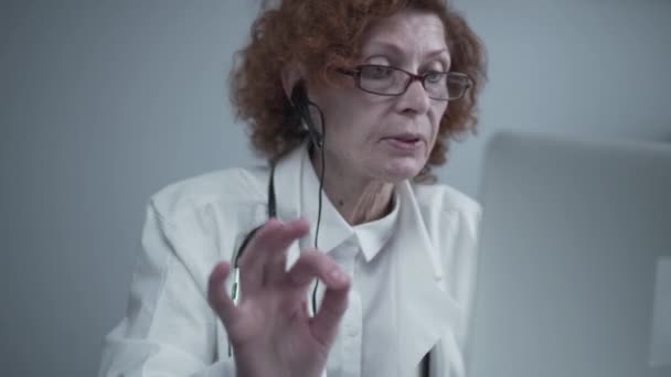 Servizi di telemedicina. Consulenze primarie, psicoterapia, servizi di emergenza. Medico donna parlando e gesticolando pur avendo consultazione online sul computer portatile. Medicina, concetto di assistenza sanitaria — Video Stock