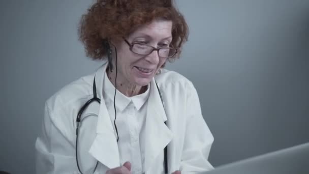 Services de télémédecine. Consultations en soins primaires, psychothérapie, services d'urgence. Médecin féminin parlant et gestualisant tout en ayant une consultation en ligne sur ordinateur portable. Médecine, concept de santé — Video