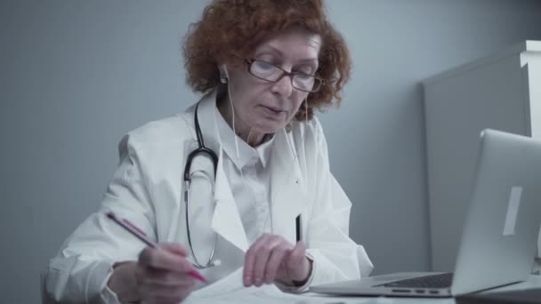 Femme d'âge moyen médecin généraliste ont un appel vidéo avec des collègues au bureau. Médecin parlant avec le patient lors d'un rendez-vous médical virtuel. Médecin parler par webcam en ligne appel vidéo sur ordinateur portable — Video