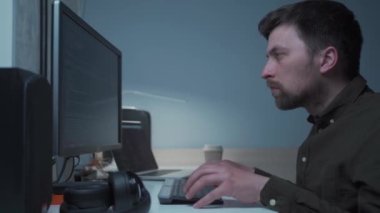 Evdeki masasında çalışan bir bilgisayar programcısı. Erkek geliştirme uzmanı işyerinde oturuyor ve yazılımla çalışıyor, bilgisayarda veri kodu yazıyor. Programlama. Geliştirme şirketi