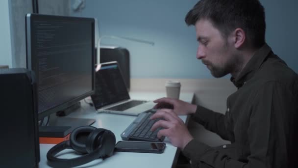 Fiatal kaukázusi férfi szabadúszó számítógépes szoftverfejlesztőként programkódot ír otthonról a karantén és a coroavírus világjárvány idején. Profi kódprogramozás. IT programozó — Stock videók