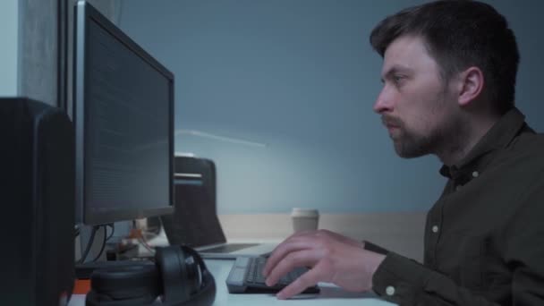 Evdeki masasında çalışan bir bilgisayar programcısı. Erkek geliştirme uzmanı işyerinde oturuyor ve yazılımla çalışıyor, bilgisayarda veri kodu yazıyor. Programlama. Geliştirme şirketi — Stok video