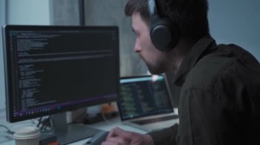 Kulaklık programcısı, bilgisayar ve dizüstü bilgisayarın arkasında yeni yazılım geliştirme çalışmaları ile gürültüyü iptal ediyor. Ofisteki bilgisayarda çalışan uygulama geliştiricisi. Evden çalışma, uzaktan çalışma konsepti