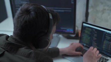 Kulaklıklı beyaz adam bilişim kodlayıcı yazılım mühendisi dizüstü bilgisayar yazma kodu geliştirme programı Java dil uygulamasını ekran web sistemi uygulama geliştirme kavramında kullanıyor