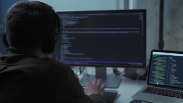 Programmeur dans les écouteurs annuler le bruit de travail sur le développement de nouveaux logiciels derrière l'ordinateur et l'ordinateur portable. Développeur d'applications travaillant sur ordinateur au bureau. Travail à domicile, concept de travail à distance — Video