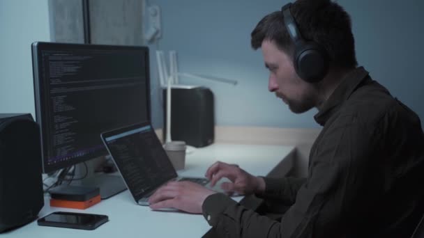 Conceito de trabalho inteligente em confinamento. Homem programador em fones de ouvido sentado no local de trabalho do computador em casa escritório. Codificação, programação. Engenheiro de software trabalhando em código de programação para novo projeto — Vídeo de Stock