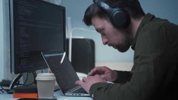똑똑하다는 개념 이 봉쇄되어 있습니다. 헤드폰을 끼고 집에 있는 컴퓨터 사무실에 앉아 있는 남자 프로그래머입니다. 코드, 프로그래밍. 새로운 프로젝트를 위한 프로그래밍 코드 작업중인 소프트웨어 엔지니어 — 비디오