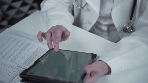 Idős női szakorvos, aki digitális tablettát használ a kórházban. Orvos kezében modern tech pad eszköz dolgozik online segítségével távorvoslás szolgáltatások alkalmazások. Egészségügyi technológiai koncepció — Stock videók