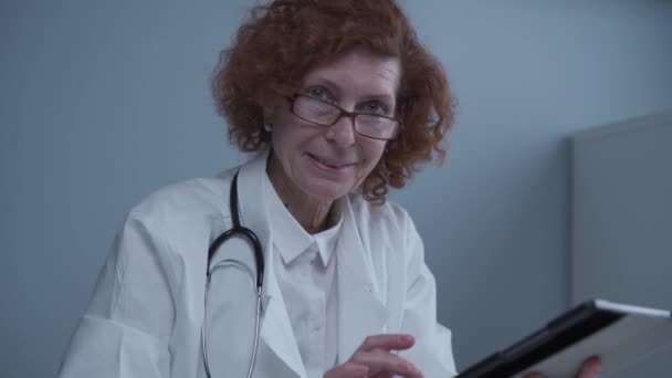 Médecin professionnel senior femme travaillant avec tablette numérique application de télémédecine à distance dans le bureau de l'hôpital travaillant en ligne. Technologie des soins de santé concept de cybersanté. Coronavirus, COVID-19 — Video