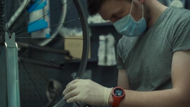 自行车修理工在验尸官检疫期间穿着护目镜和手套，在自行车维修车间工作，这是新的规范。戴医疗面罩的自行车轮式机械修理 — 图库视频影像