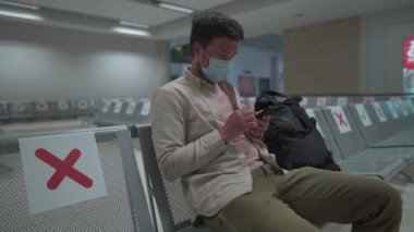 Kıbrıs 'taki boş havaalanında uçak bekliyor. Boş Paphos terminalinde sosyal mesafe işaretiyle oturan bir adam. Karantina sırasında uçuşlar iptal edildi. Coronavirus havayollarının çöküşü