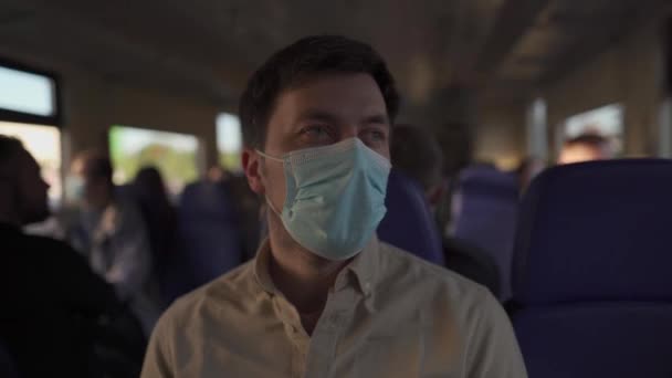 男は電車で顔マスクを着て旅行。Covid-19パンデミックの際に鉄道で移動する際の社会的距離。面をつけた公共交通機関の列車で働く男性通勤。新常識 — ストック動画