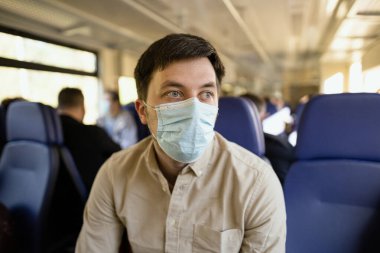 Toplu taşıma aracıyla güvenli bir şekilde gidin. Koruyucu maskeli tren yolcusu, vagonda sosyal mesafesi olan bir koltukta oturuyor, yeni norm. Coronavirus salgınında seyahat