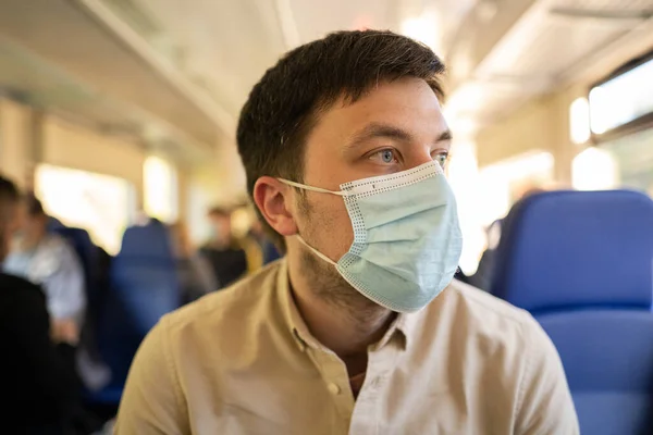 Человек, путешествующий на поезде в маске. Социальное дистанцирование во время пандемии Ковид-19. Мужчины ездят на работу в общественном транспорте в маске. Новая концепция норм — стоковое фото