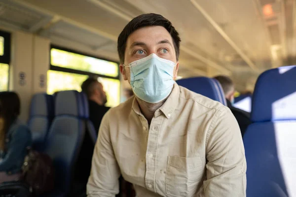 Male passenger wearing face mask during covid-19 lockdown inside train. New normal lifestyle concept. Social distancing when traveling by public transport. Commuting during coronavirus pandemic