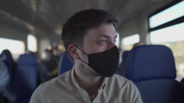 Trenin içindeki tecrit sırasında yüz maskesi takan bir erkek yolcu. Yeni normal yaşam tarzı konsepti. Toplu taşıma araçlarıyla seyahat ederken sosyal mesafeler. Coronavirus salgını sırasında işe gidip gelmek
