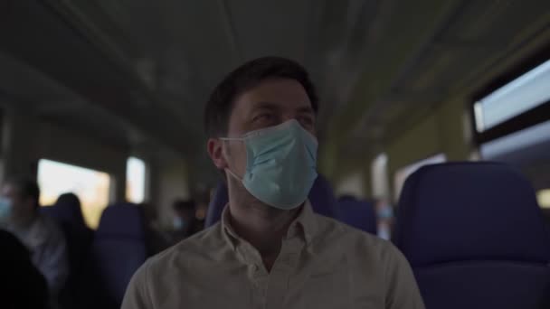 Άνδρας επιβάτης με μάσκα προσώπου κατά τη διάρκεια κλειδώματος covid-19 μέσα στο τρένο. Νέα έννοια του φυσιολογικού τρόπου ζωής. Κοινωνική απόσταση όταν ταξιδεύετε με τα μέσα μαζικής μεταφοράς. Μετακίνηση κατά τη διάρκεια της πανδημίας coronavirus — Αρχείο Βίντεο
