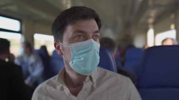 乘坐公共交通工具安全地旅行.带防护面罩的列车乘客坐着社会距离的座位出行，这是一种新的规范。大肠癌大流行期间的旅行 — 图库视频影像