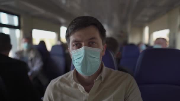 Άνδρας επιβάτης με μάσκα προσώπου κατά τη διάρκεια κλειδώματος covid-19 μέσα στο τρένο. Νέα έννοια του φυσιολογικού τρόπου ζωής. Κοινωνική απόσταση όταν ταξιδεύετε με τα μέσα μαζικής μεταφοράς. Μετακίνηση κατά τη διάρκεια της πανδημίας coronavirus — Αρχείο Βίντεο