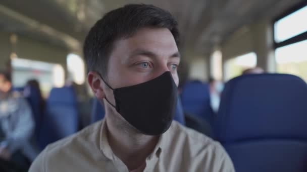 Viaje com segurança covid 19 em transportes públicos. Passageiro de trem com máscara protetora viaja sentado no assento com distância social em carruagem ferroviária, nova norma. Viagem durante a pandemia de coronavírus — Vídeo de Stock