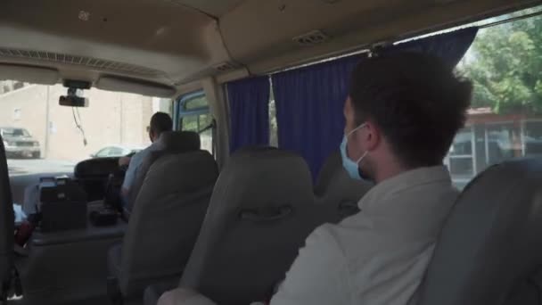 Viaje en transporte público durante el cierre, coronavirus cuarentena en Chipre en la ciudad de Paphos. El hombre caucásico se sienta en máscara protectora solo en un pequeño y vacío autobús viejo. Nueva norma y distancia social covid 19 — Vídeos de Stock