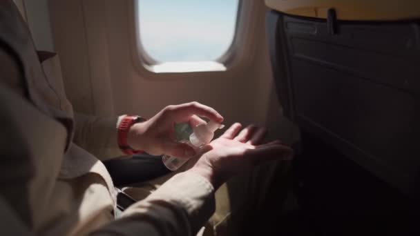 Homme dans l'avion, avion désinfecte les mains appliquer du gel avec de l'alcool de désinfection pour les mains contre la pandémie Covid-19, prévention de la santé. Vol pendant le coronavirus, passager utilise un antiseptique à bord — Video