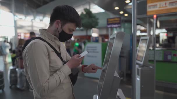 Passagier im maskierten Self-Check-in-Gepäck für Flug in Maschine im Terminal, Reisesicherheitskonzept, neue normale soziale Distanz während des Coronavirus-Ausbruchs. Mann nutzt Selbstbedienungs-Check-in am Flughafen — Stockvideo